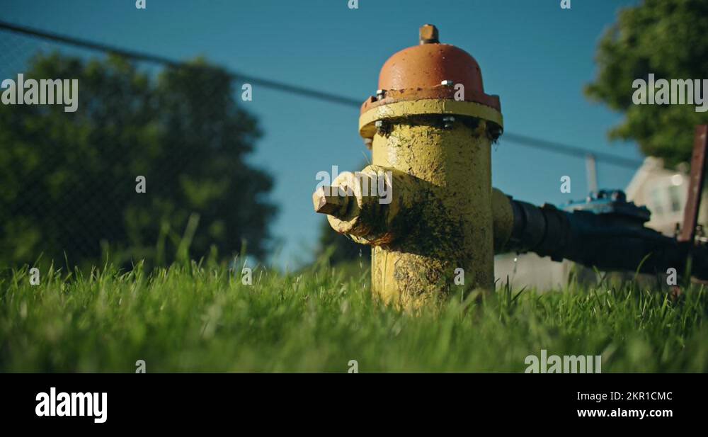 Leaking Fire Hydrant in Grass Closeup. Water Dripping from Leaky Pipe