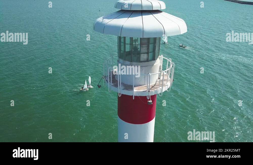 Striped Lighthouse And Sailing Small Boats In The Coastal Harbor Of ...