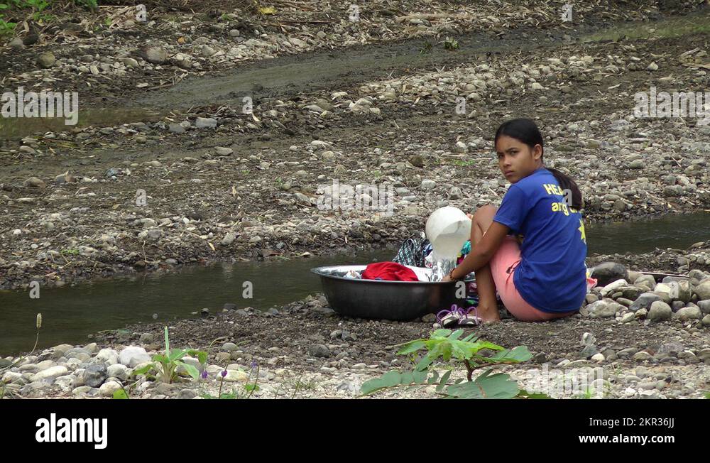 Filipino woman hand washing clothes at a river in the Philippines Stock