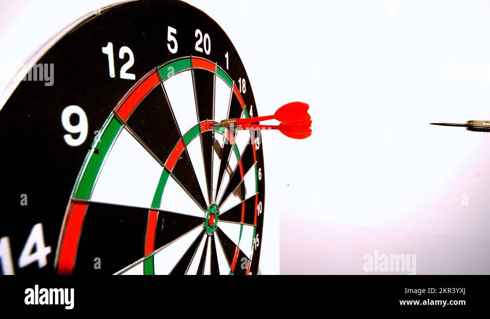 Dart hitting the dart board between two other darts side view Stock