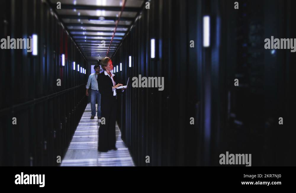 People working in computer server room data center. Walking along rows ...