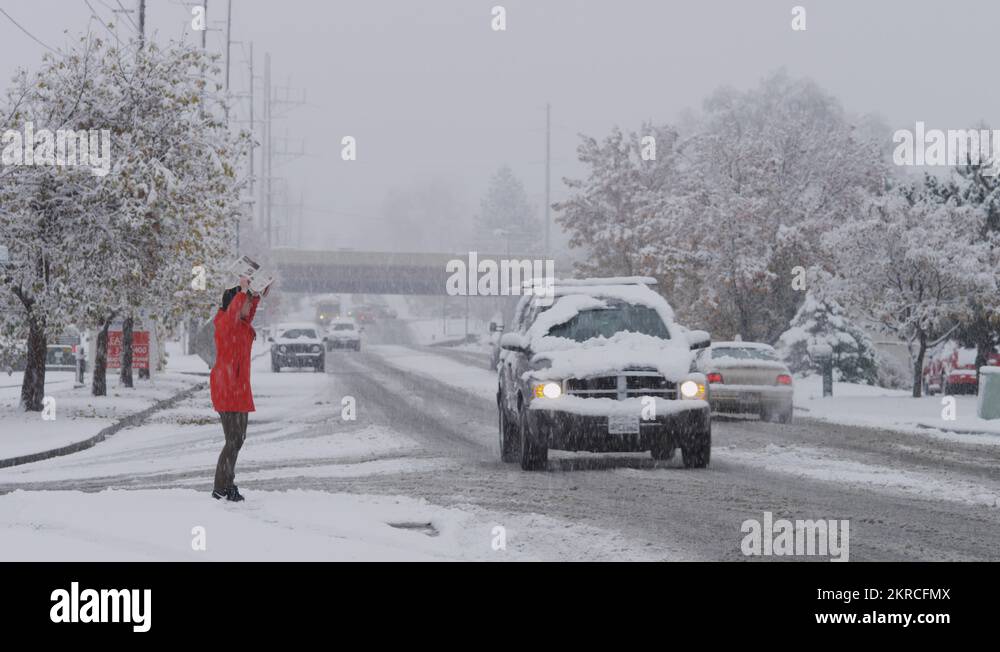 Snow falling on woman crossing busy urban street / Orem, Utah, United