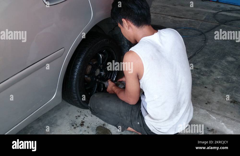 Changing tyre Man tightening lug nuts of a new tyre using impact wrench Stock Video Footage Alamy