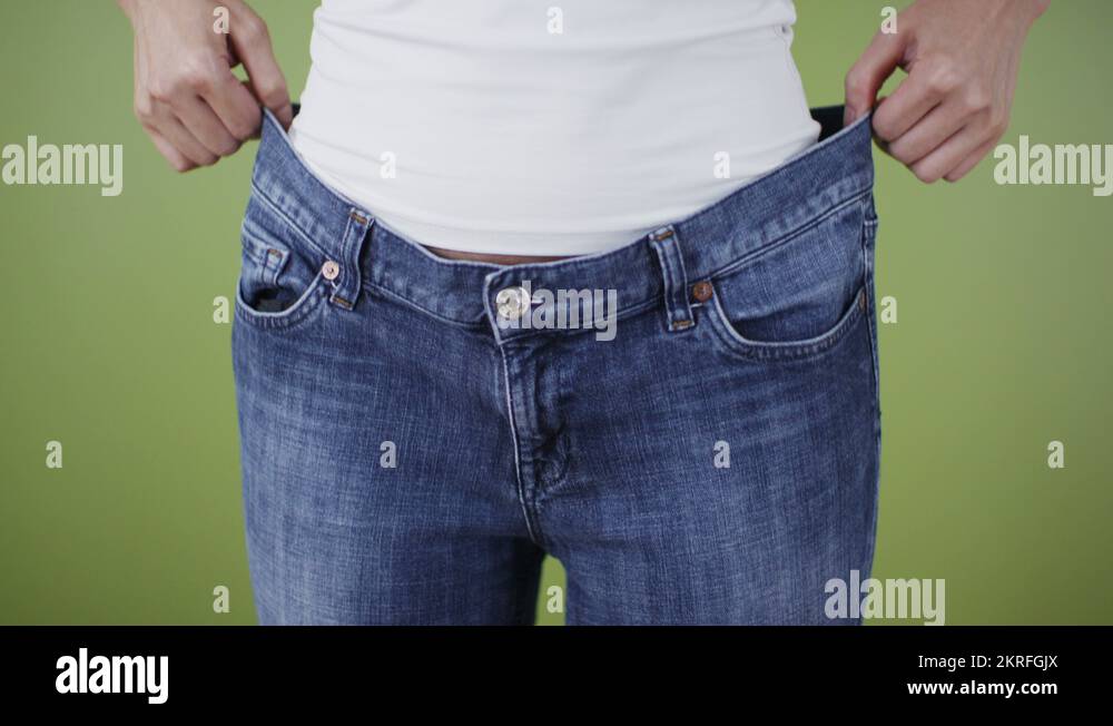 Woman who has lost weight pulling on jeans that are too big Stock Video