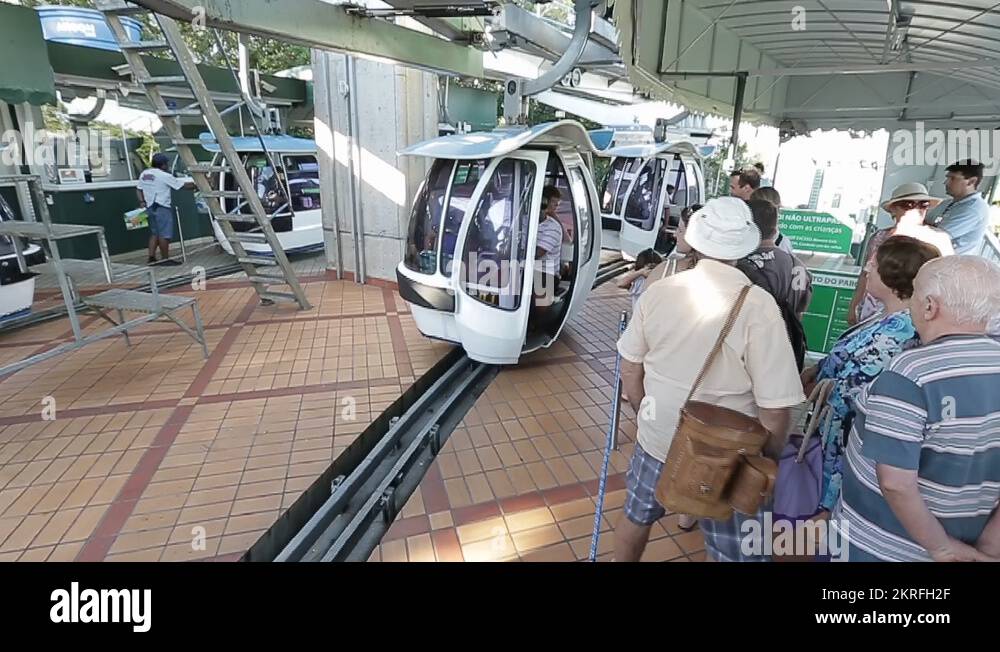 cable car arriving at the station where people wait for boarding Stock
