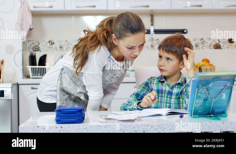 Little boy doing homework in the kitchen with his mother Stock Video ...