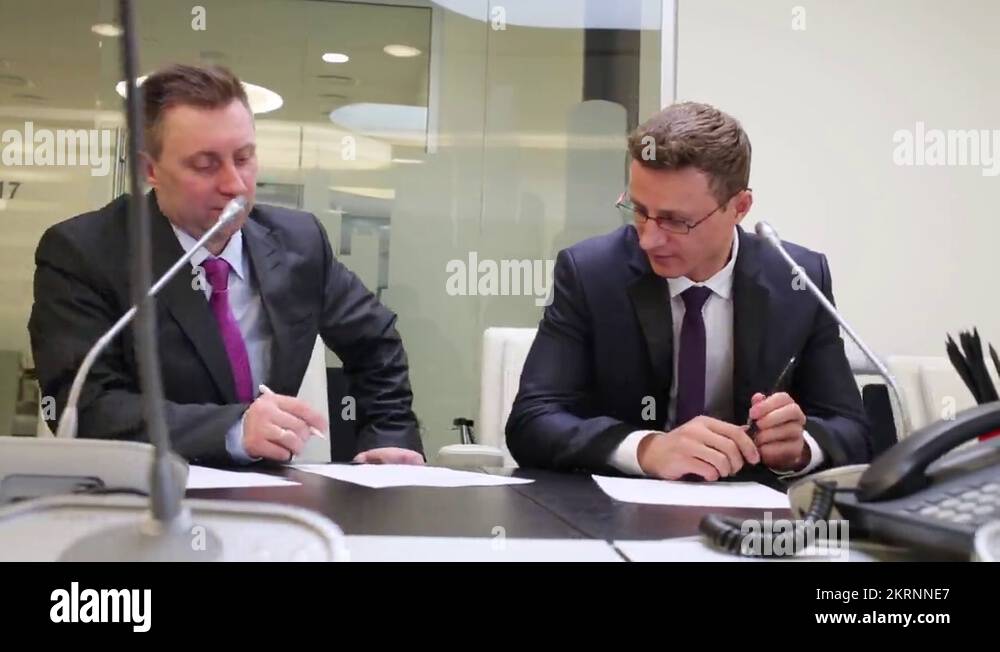 Two businessmen get up from table in meeting room and shake hands Stock
