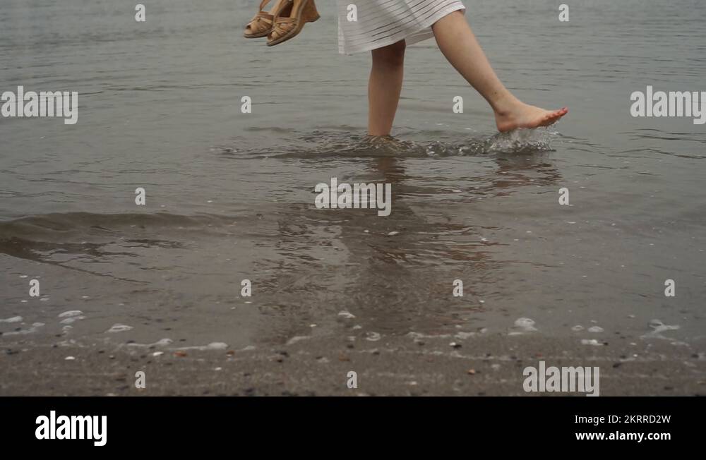 Young Japanese woman barefoot in the water at city beach, Tokyo, Japan ...