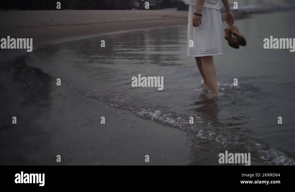 Young Japanese woman barefoot in the water at city beach, Tokyo, Japan ...