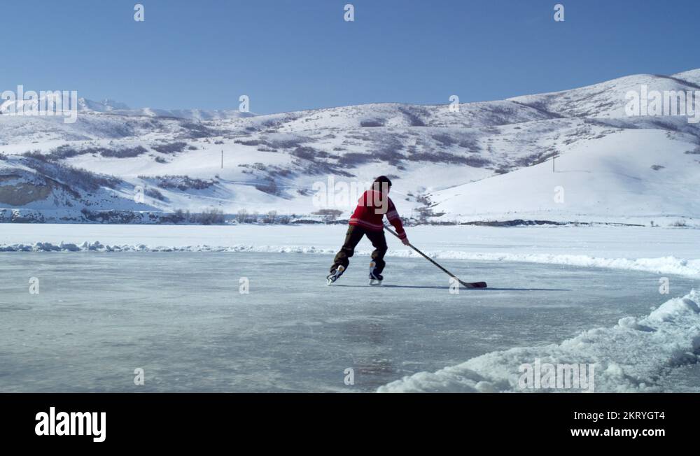 Young boy dribbling a hockey puck back and forth at an outdoor rink