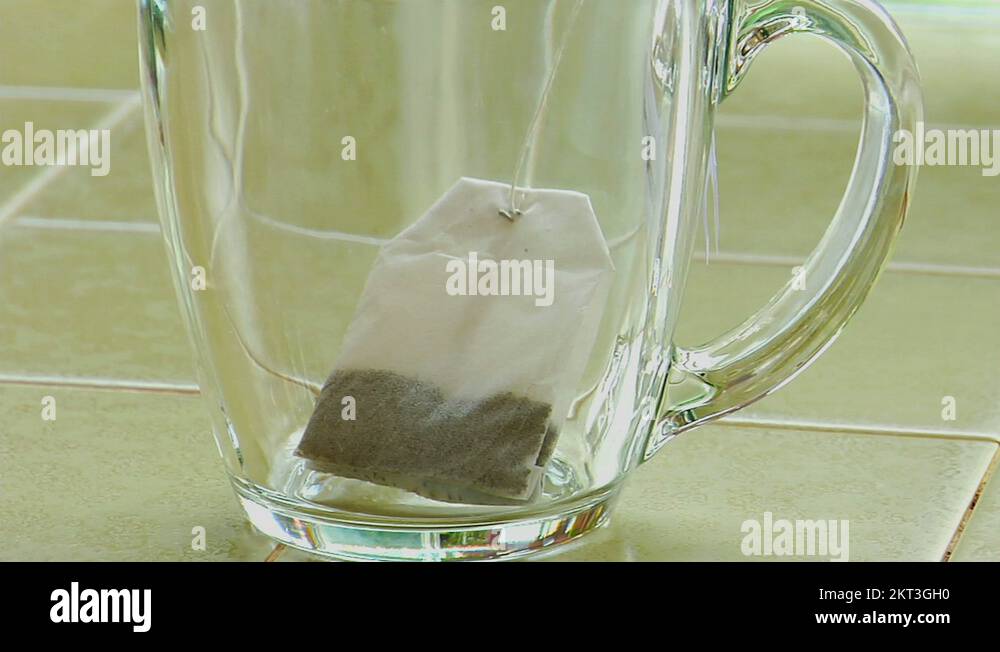 Boiling water poured over a tea bag in a clear glass coffee cup Stock