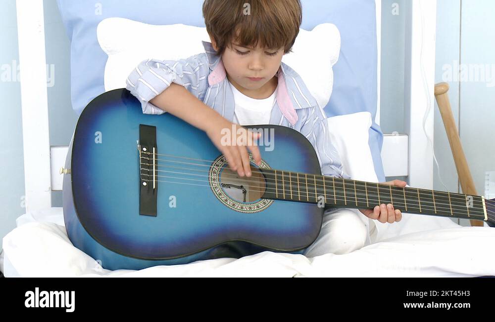 Little boy playing guitar on bed Stock Video Footage Alamy