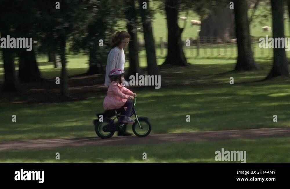 Parent teaching a child to how to ride bicycle without stabilisers in