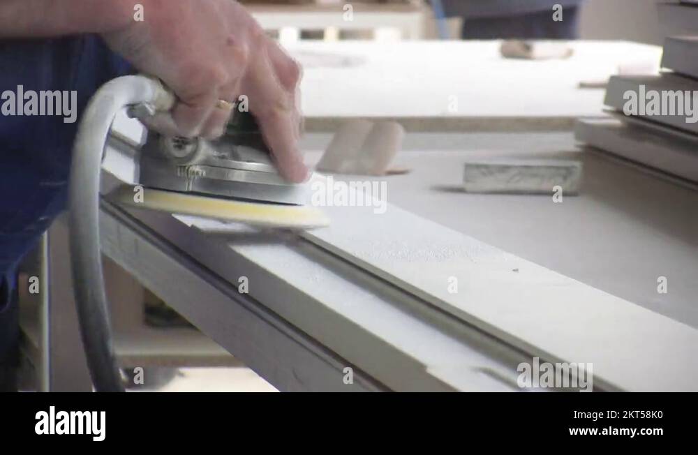 Worker using a power sander to smooth part of the doors frame Stock