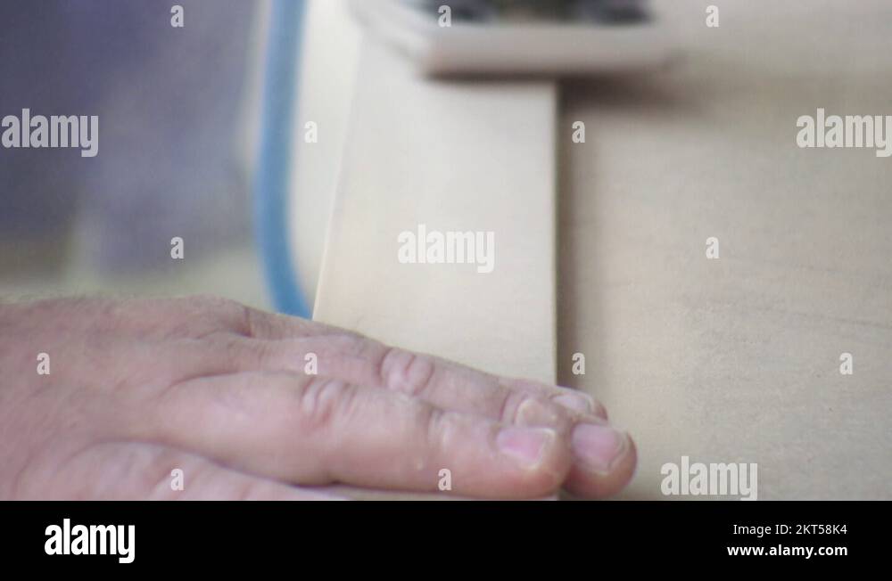 Worker using a power sander to smooth part of the doors frame Stock
