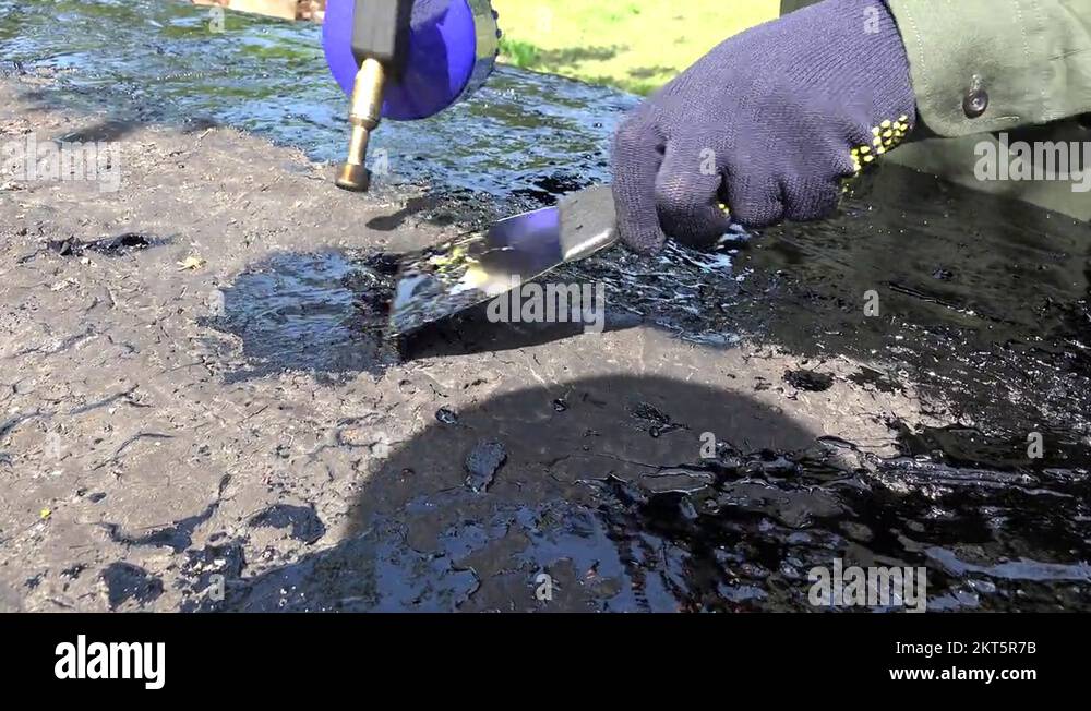 Worker man hands repair lay tar on roof surface with special tools. 4K