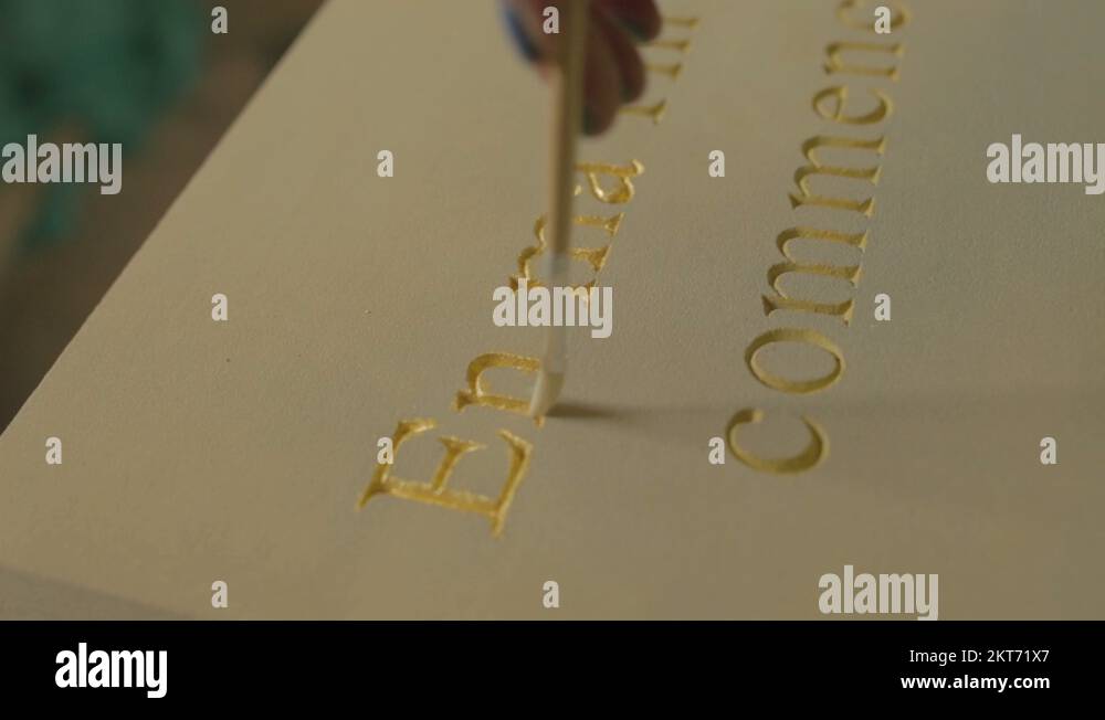 A female using a paint bursh to apply gold leaf to a stone plinth Stock