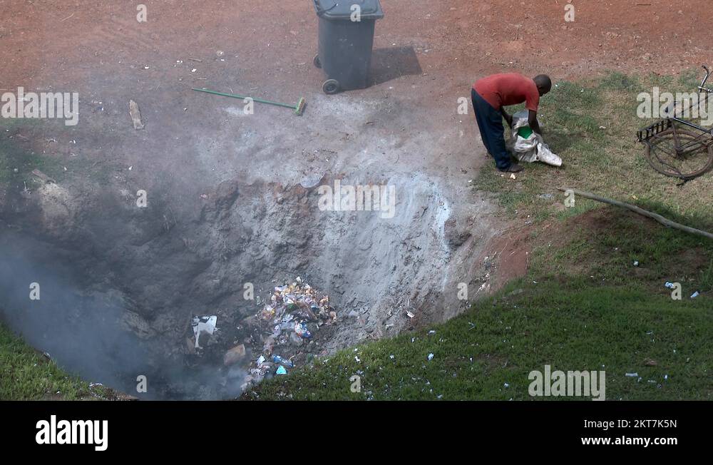 African informal garbage collector, in a fire hole to burn trash