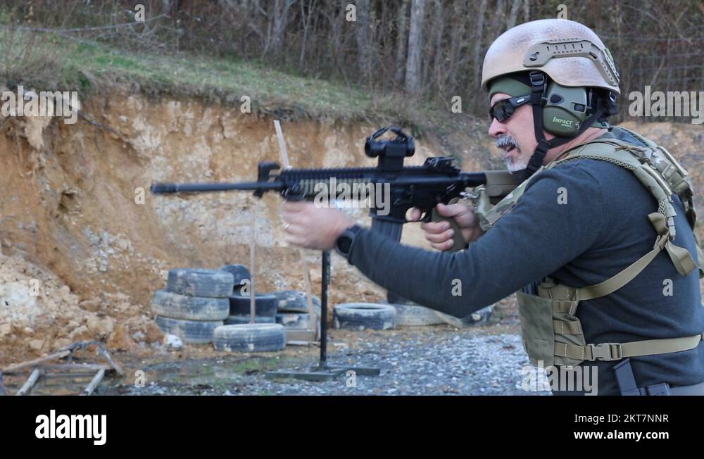 Man with military vest and helmet firing an AR15 rifle at a gun range