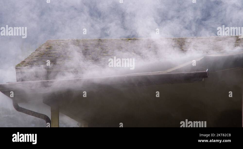 Smoke escaping from around the gutter on the eaves of a burning house