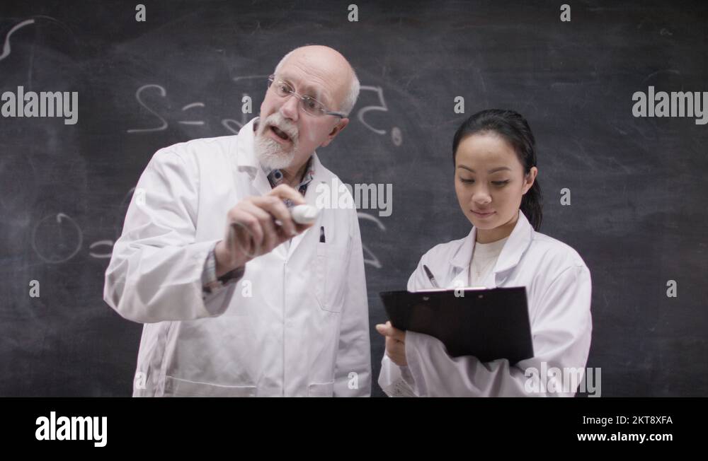 Scientists Using Math 4K Scientists in white coats writing math formulas on glass screen in ...