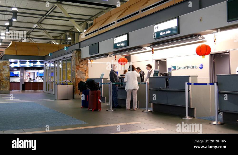 Passengers with luggage at Cathay Pacific check in counter inside YVR