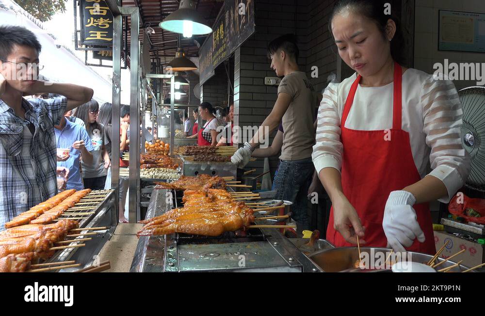 Chinese street vendors grill kebabs at busy food snack alley in Wuhan