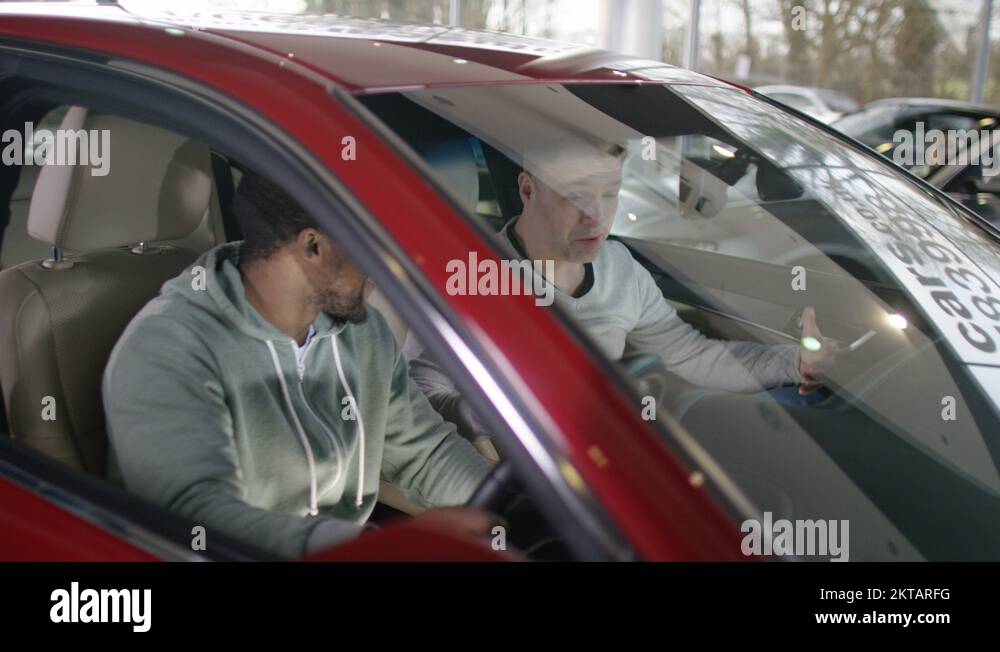 4K Salesman talking to men in car dealership & showing them new car