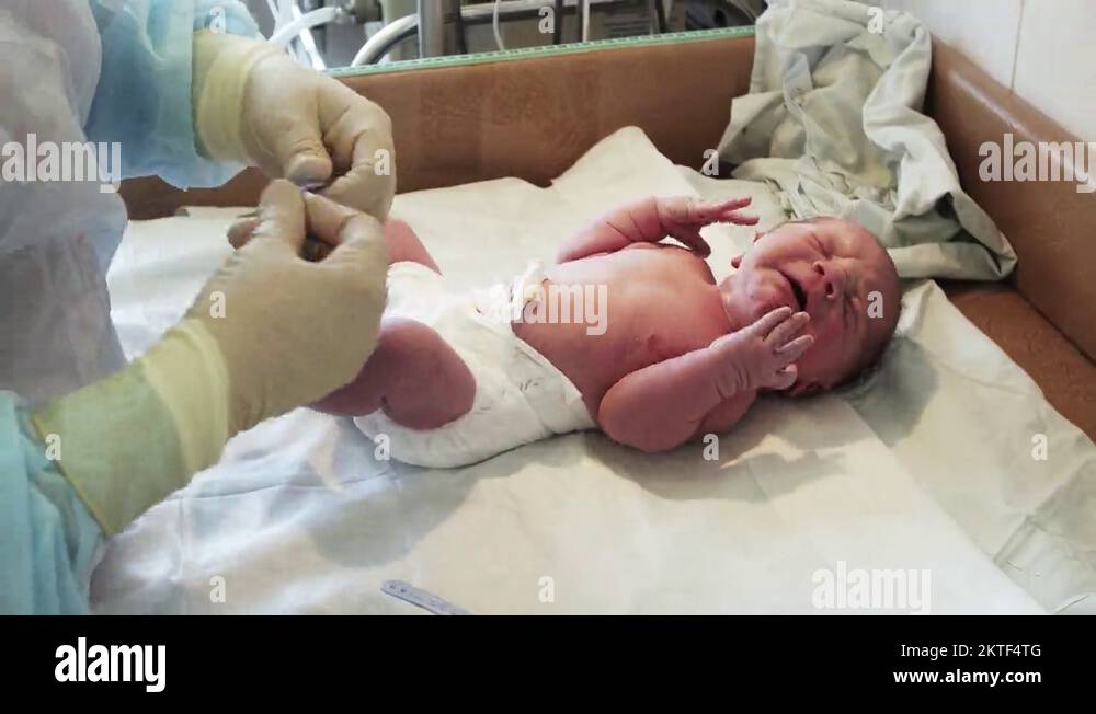 Nurse put on blue bracelet on hand of newborn crying baby in diapers