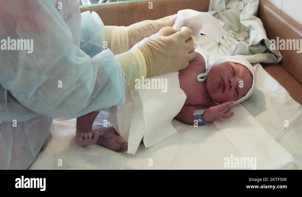 Nurse put on disposable diaper on newborn crying baby in diapers after
