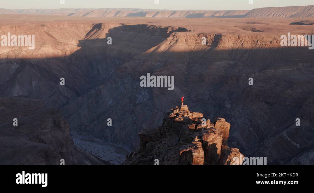 4K Panning shot of Male tourist standing on rock pinnacle taking in the