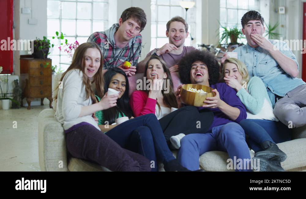 Excited group of young sports fans watching TV and spilling popcorn