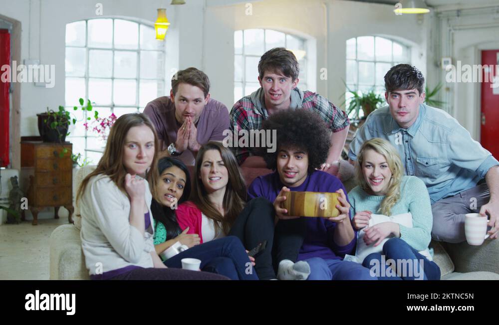 Excited group of young sports fans watching TV and spilling popcorn