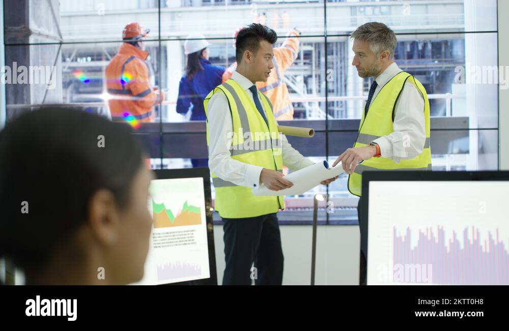 4K Power station control room workers checking plans & watching