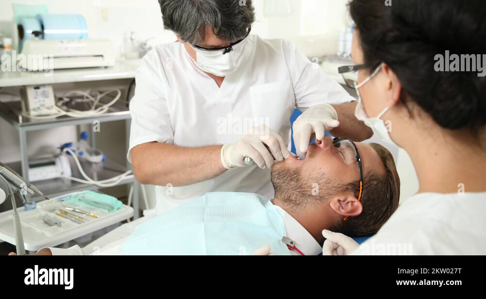 dentist-man-surgery-pull-up-tooth-using-removal-tool-patient-lying