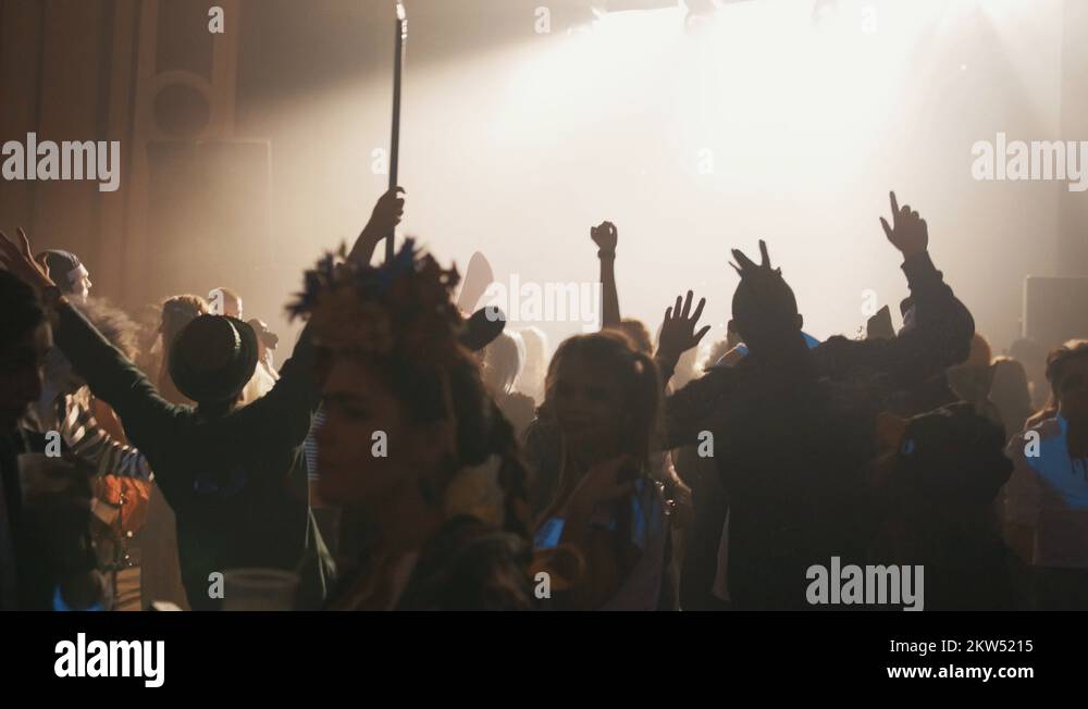 People in halloween costumes dance at party in night club, flashing
