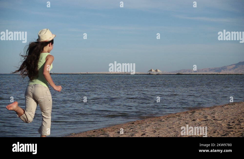 Young girl running away at the beach in Egypt resort, slow motio Stock