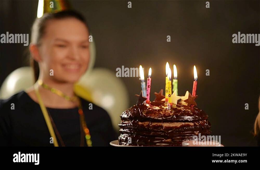 Pretty Lady in Cap is Blowing out Her Birthday Candles on Chocolate