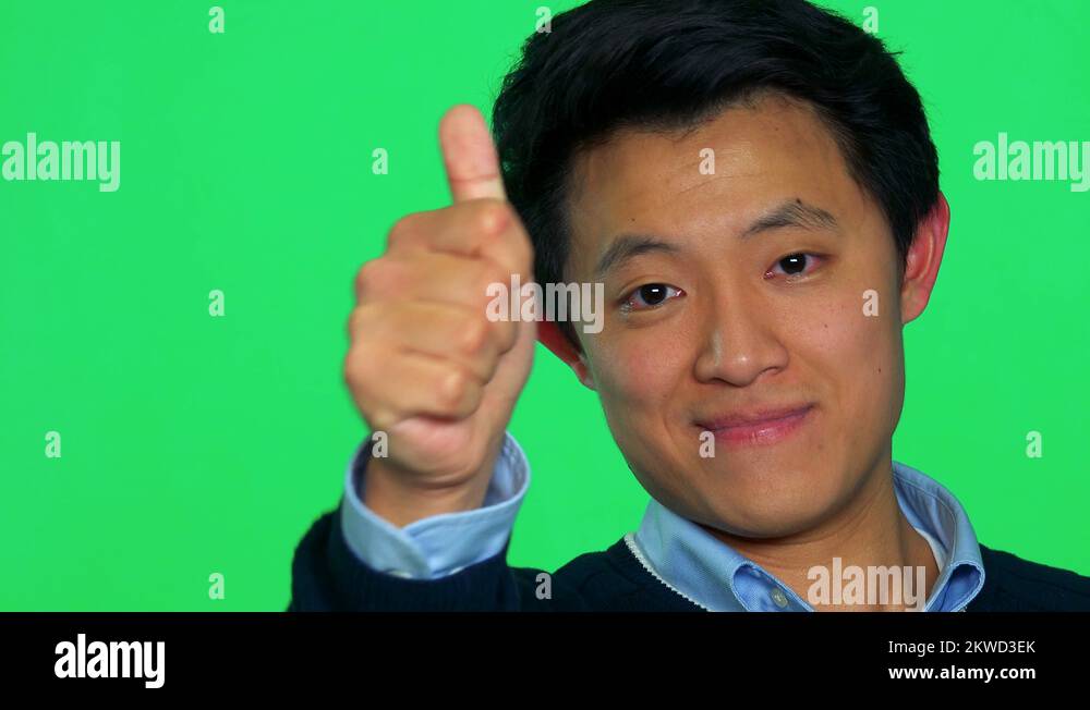 A Young Asian Man Smiles And Shows A Thumb Up To The Camera Green