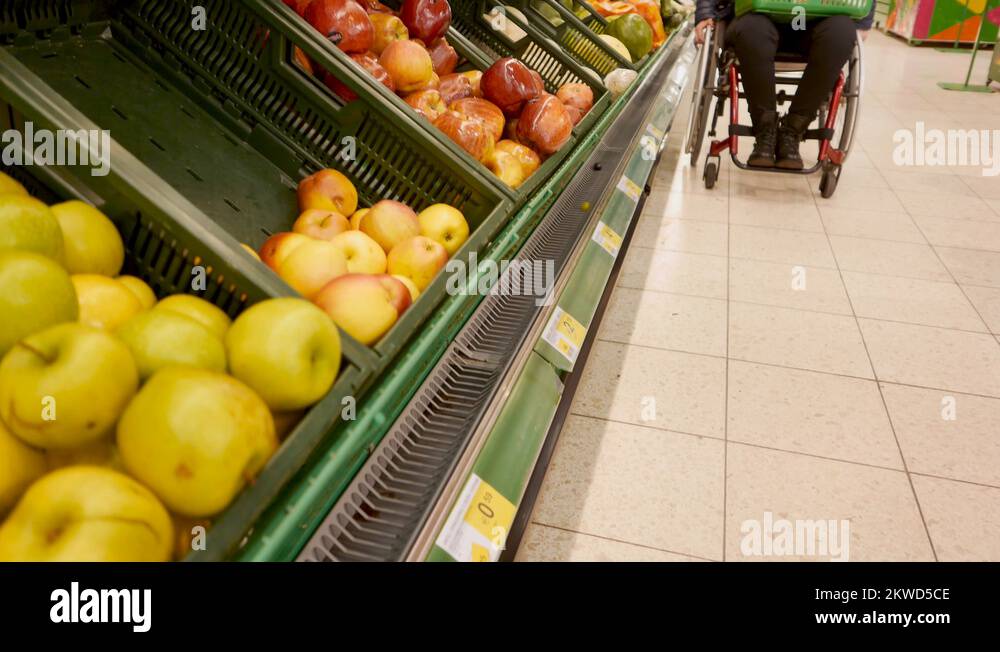 Disabled woman in a wheelchair choosing fruits and vegetables Stock