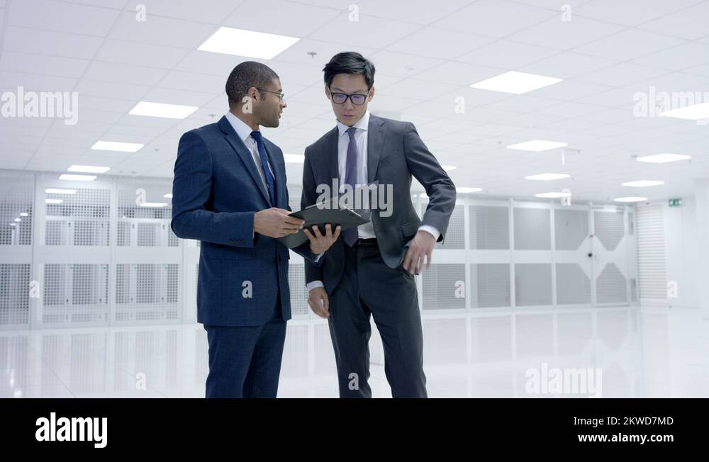 4K Business people looking around large data center with rows of server ...