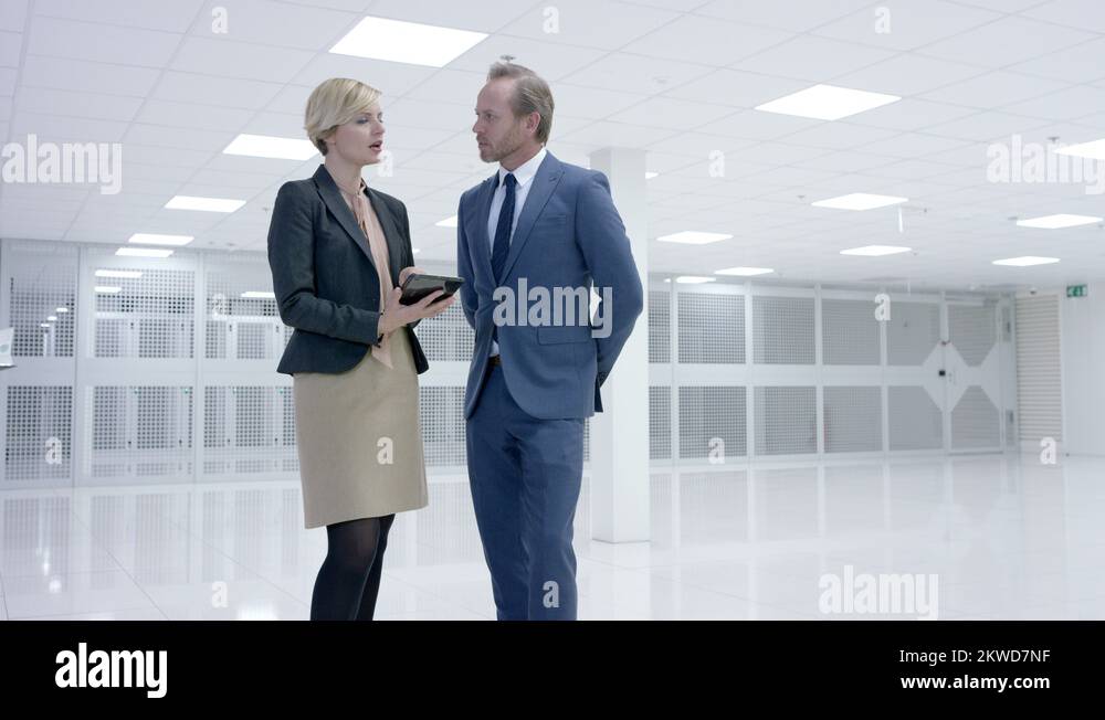 4K Business people looking around large data center with rows of server ...