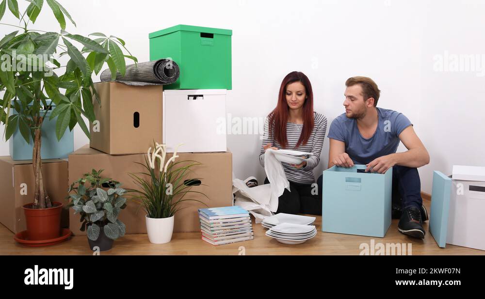Beautiful Young Couple Moving Out Packing Fragile Ceramics for New