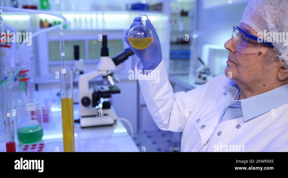 Expert Elderly Woman Biochemist Examining Sample Liquid Spinning Tube