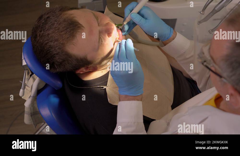 Dentist in Glasses Pulls The Saliva Ejector From the Oral Cavity of the