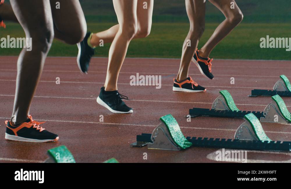 4K Female runners at athletics track crouching at starting blocks