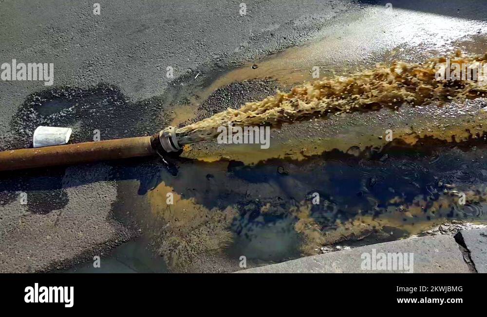 Hot water flowing from a hose on a asphalt. Pipeline break. Accident