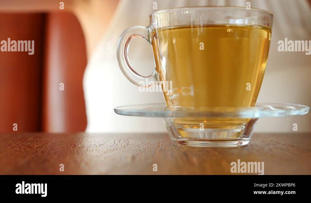 The girl puts a piece of brown sugar in a transparent mug with green