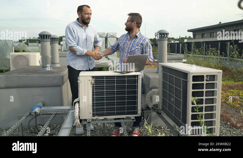 Men making deal and shaking hands standing near air conditioning on