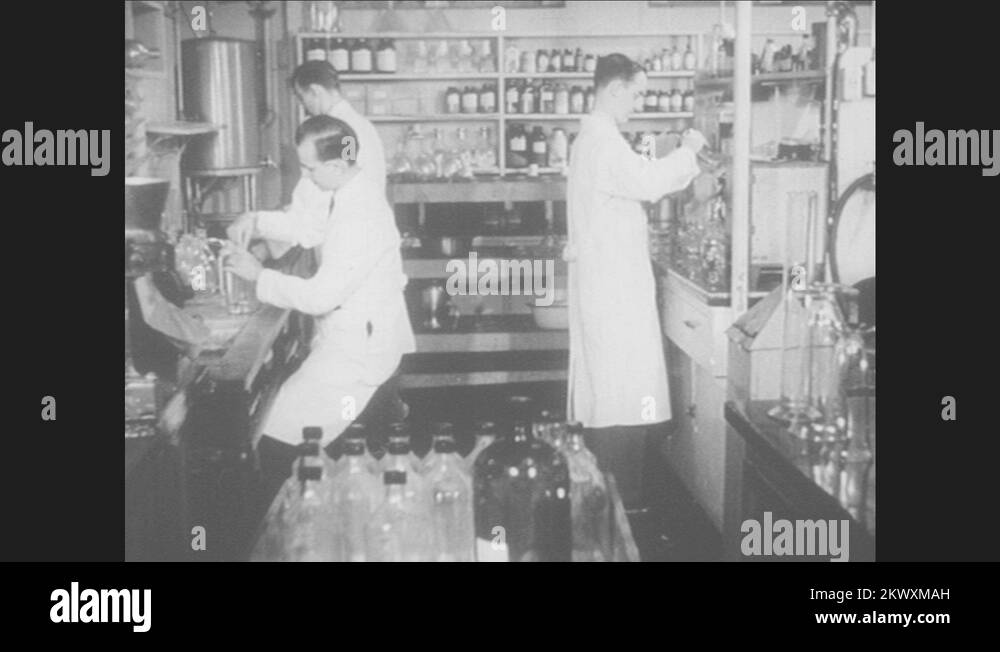 1940s Three pharmacists in chemistry lab hard at work. Man turns valve